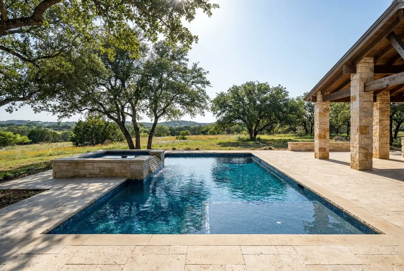 Pool with a raised limestone spa and travertine deck in the Texas Hill Country